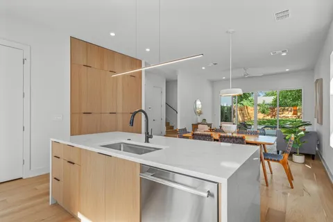 a kitchen with a sink a counter top space and living room view