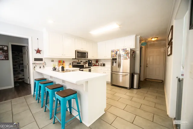 a kitchen with stainless steel appliances a refrigerator a stove a sink a dining table and chairs