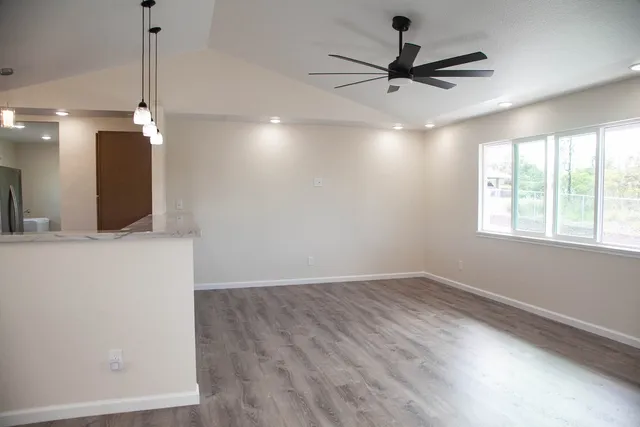 a view of an empty room with a ceiling fan and window