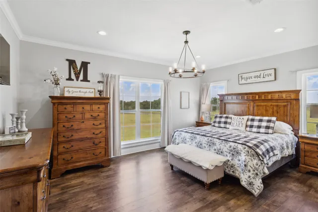 a bedroom with a bed a dresser and wooden floor