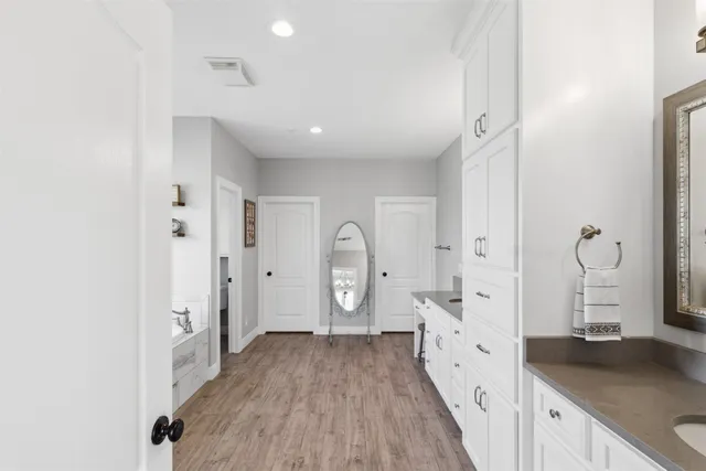 a large space with white cabinets and wooden floor