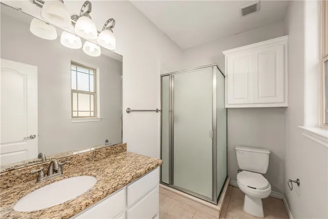 a bathroom with a granite countertop sink toilet a mirror and a shower