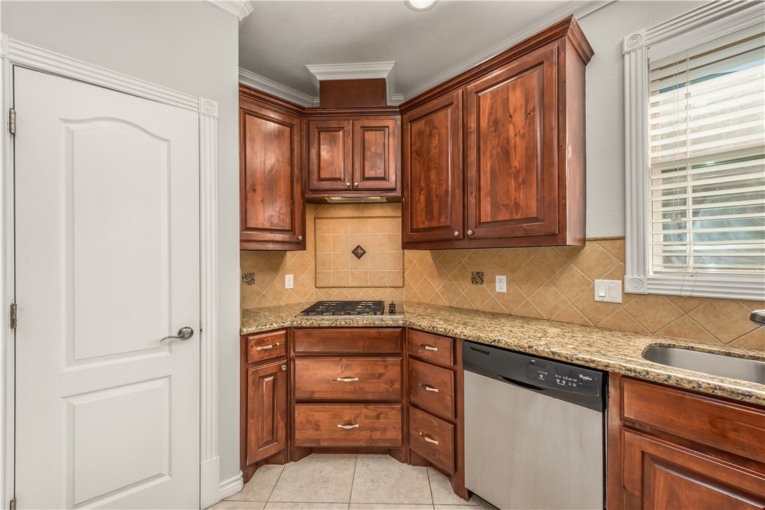 3916 Incourt Lane College Station, TX 77845 - Photo 5 of 15 Kitchen with stainless steel appliances, decorative backsplash, light stone counters, crown molding, and light tile patterned floors