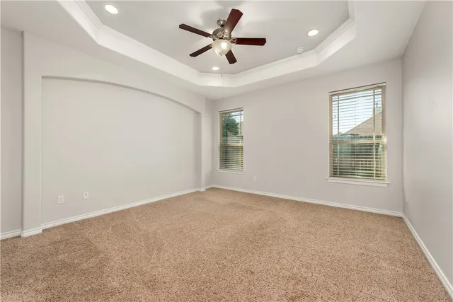 an empty room with ceiling fan and windows