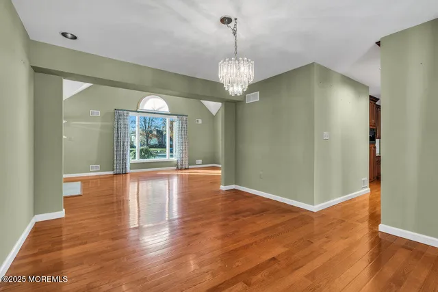 a view of a room with wooden floor chandelier and windows