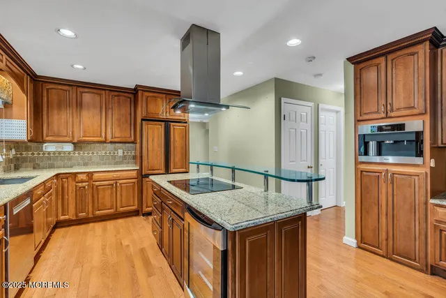 a kitchen with granite countertop a refrigerator a sink dishwasher and wooden cabinets with wooden floor
