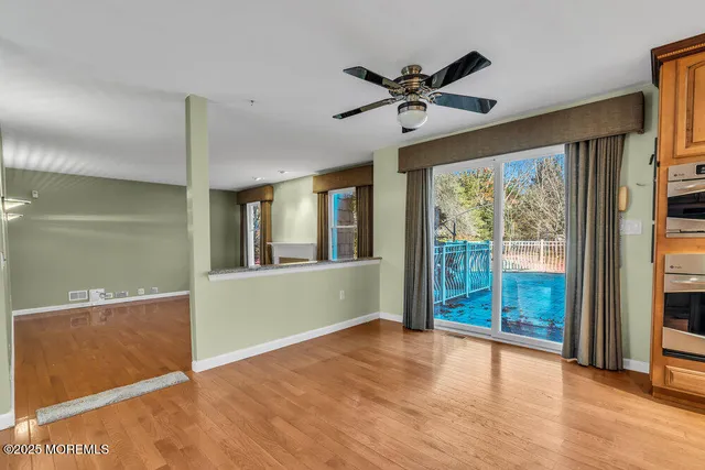a view of an empty room with window and wooden floor
