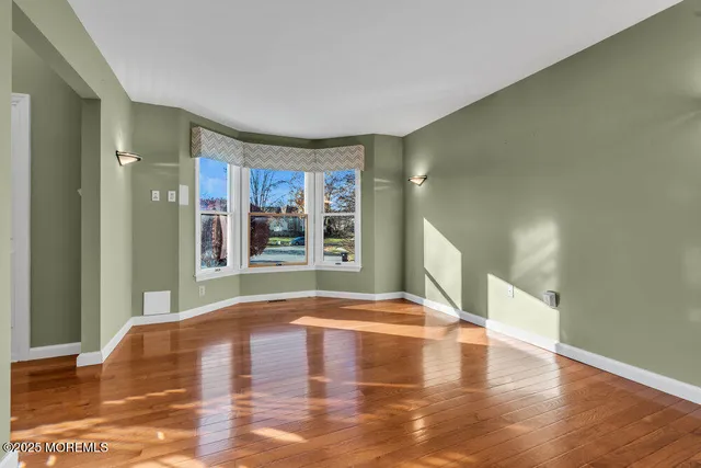 a view of an empty room with window and wooden floor