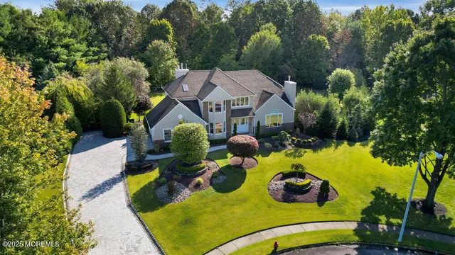 an aerial view of a house with swimming pool and large trees