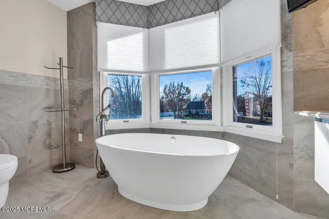 an empty room with wooden floor chandelier fan and windows