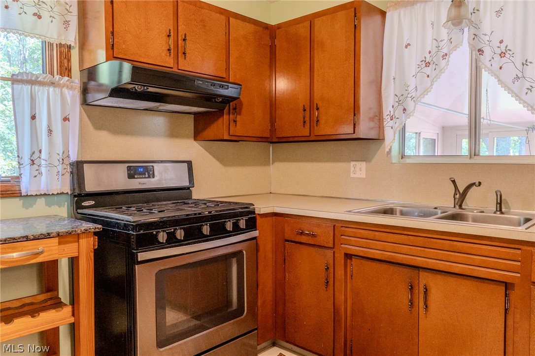 2848 Pressler Road Uniontown, OH 44685 - Photo 17 of 37 Wood-finish cabinetry, stainless steel range, dual basin sink, and a light-toned countertop