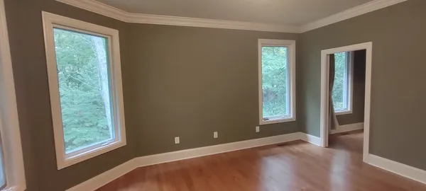 a view of an empty room with wooden floor and a window