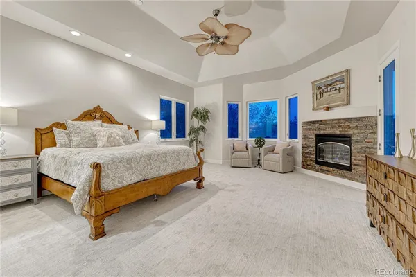 a spacious bedroom with a bed a ceiling fan and a fireplace