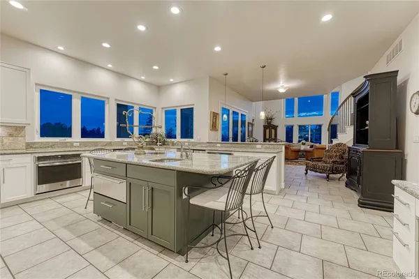 a kitchen with stainless steel appliances granite countertop a sink a stove a dining table and chairs