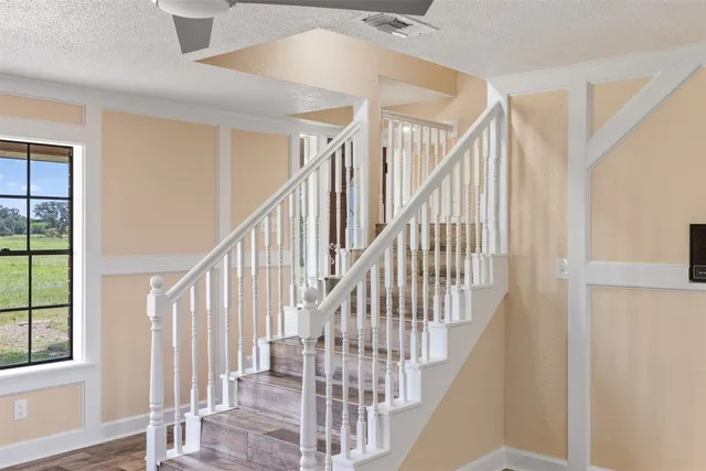 a view of staircase with lots of frames on wall and wooden floor