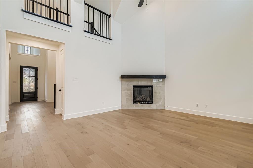 150 Longhorn Bend Rhome, TX 76078 - Photo 4 of 28 Unfurnished living room with a towering ceiling, a fireplace, light wood-style floors, and ceiling fan