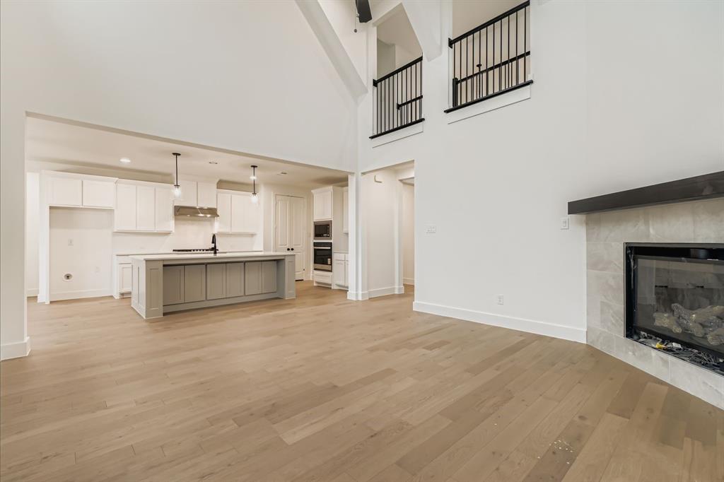 150 Longhorn Bend Rhome, TX 76078 - Photo 5 of 28 Unfurnished living room with a fireplace, light wood finished floors, and a towering ceiling