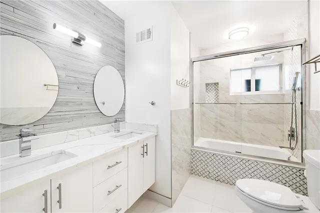 a bathroom with a double vanity sink toilet mirror and shower