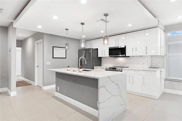 a kitchen with stainless steel appliances granite countertop a sink a stove and a refrigerator