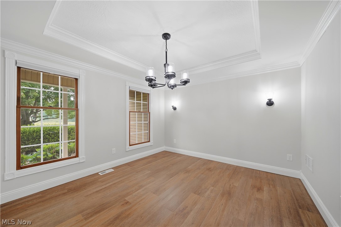 4764 Young Road Stow, OH 44224 - Photo 8 of 41 Dining room featuring wood-finish flooring, a tray ceiling with crown molding, and a contemporary black chandelier.