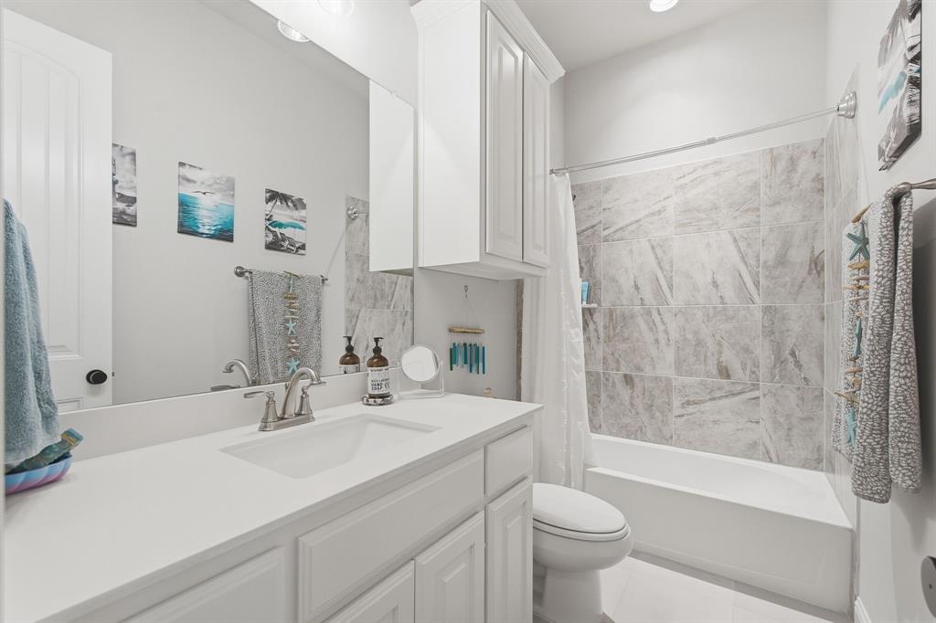 313 Tate Lane Anna, TX 75409 - Photo 17 of 30 Bathroom featuring a vanity with white cabinetry, a single basin sink, a large wall mirror, and a tub with a tile surround