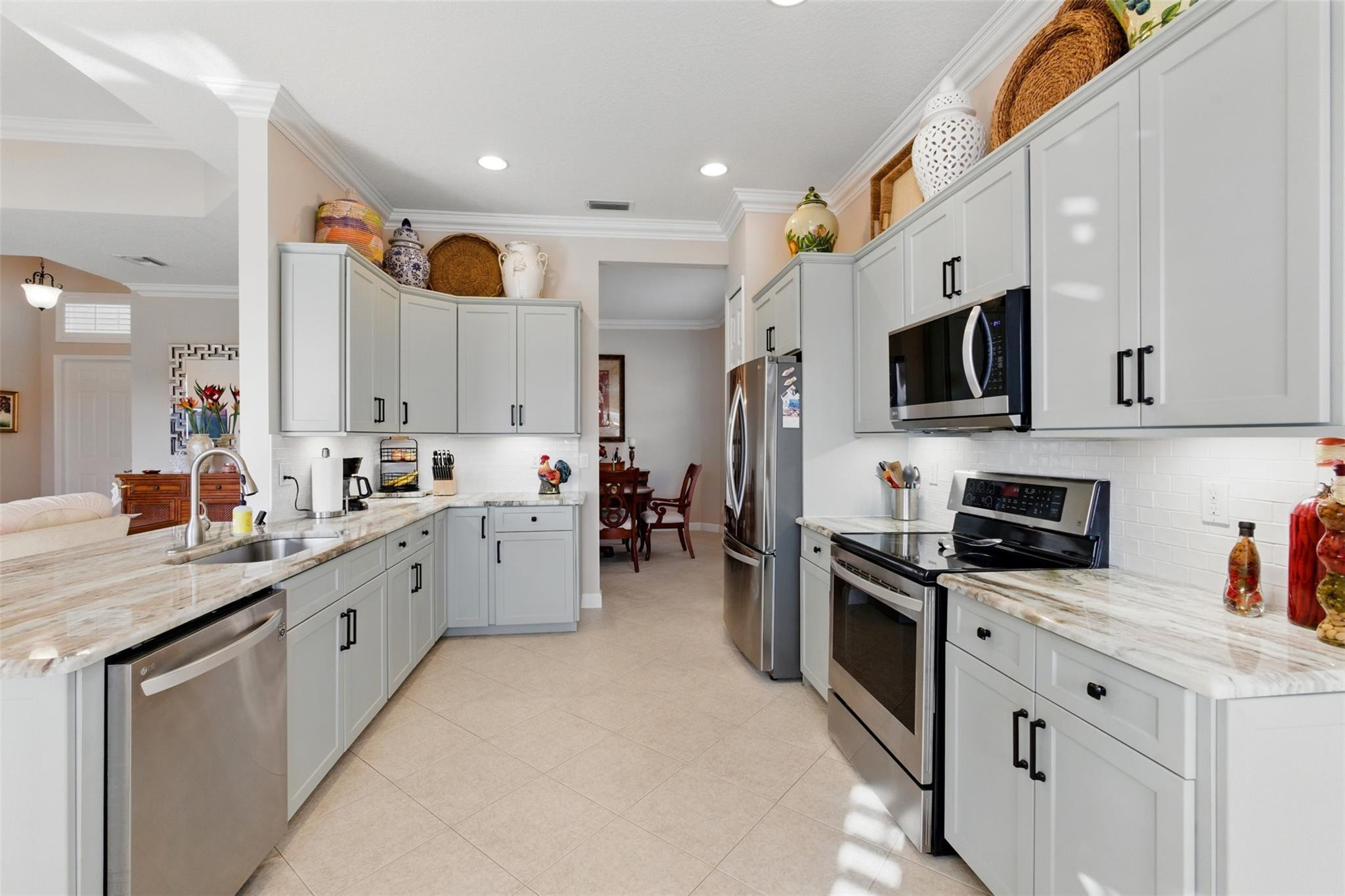 8836 First Tee Road Port St. Lucie, FL 34986 - Photo 8 of 35 a large kitchen with stainless steel appliances granite countertop a stove a sink and a microwave