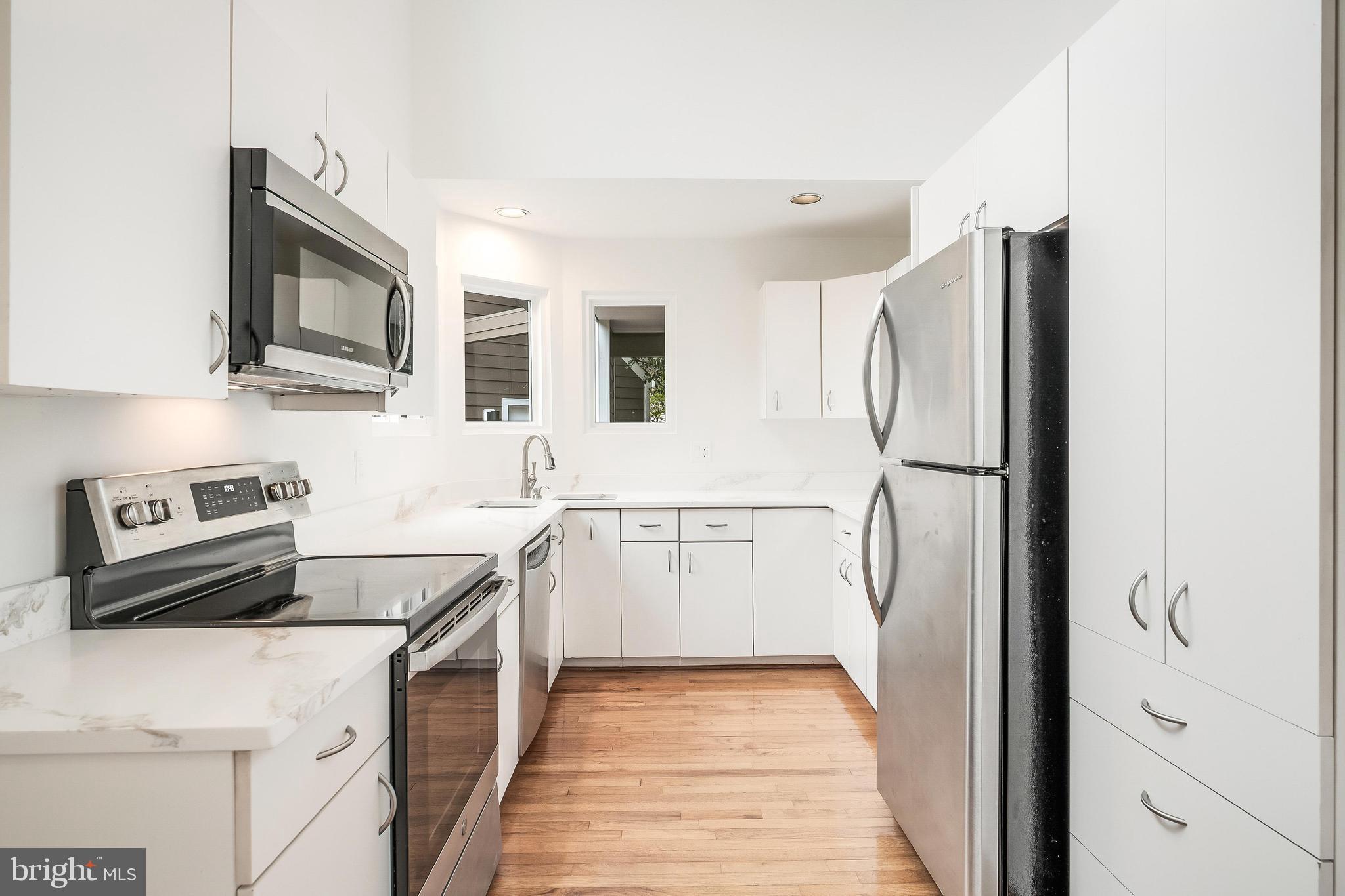 11916 Moss Point Lane Reston, VA 20194 - Photo 23 of 43 a kitchen with stainless steel appliances granite countertop a refrigerator a stove and a sink with wooden floor