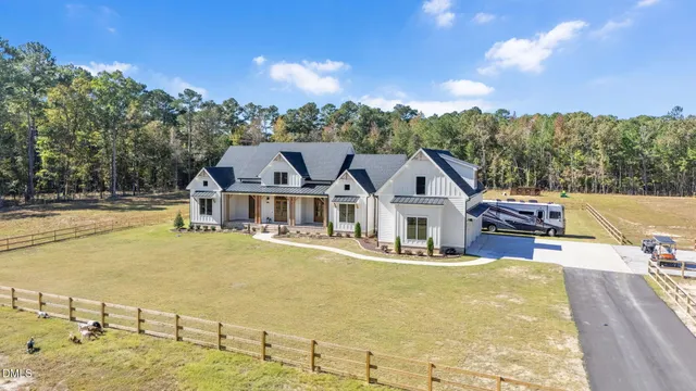 a view of a white house with a large pool and lawn chairs under an umbrella