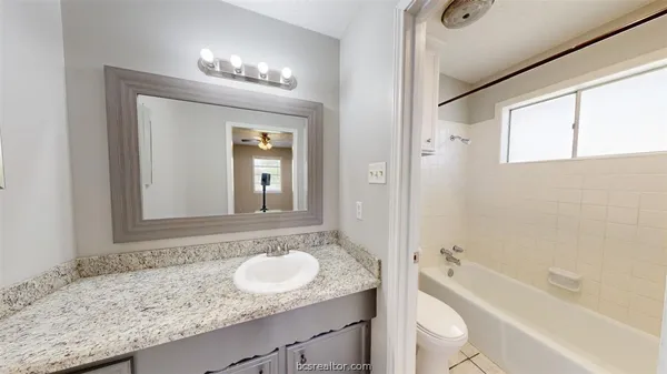 a bathroom with a granite countertop sink mirror toilet and bathtub