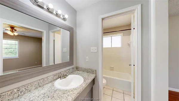a bathroom with a granite countertop sink a mirror and shower
