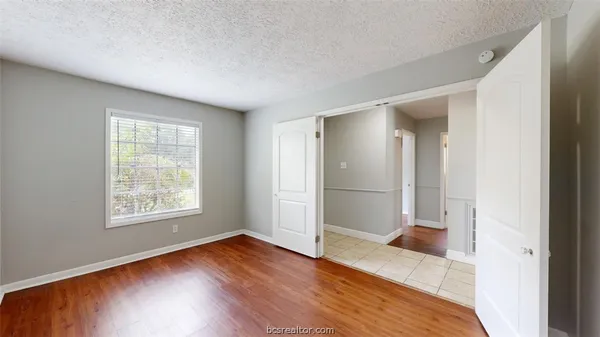 a view of an empty room with window and wooden floor