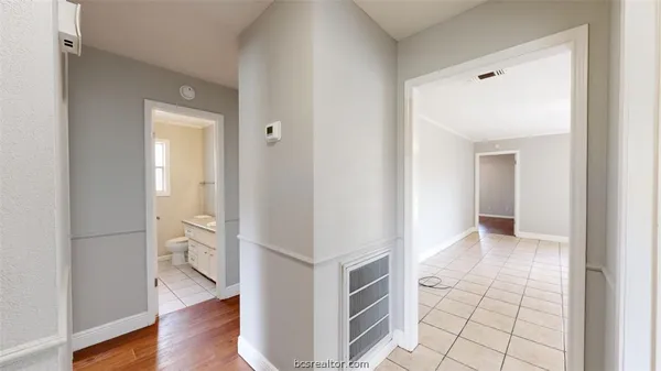a view of a hallway with wooden floor and a bathroom
