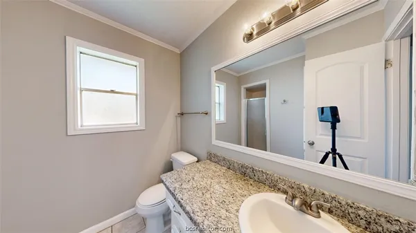 a bathroom with a granite countertop sink toilet and mirror