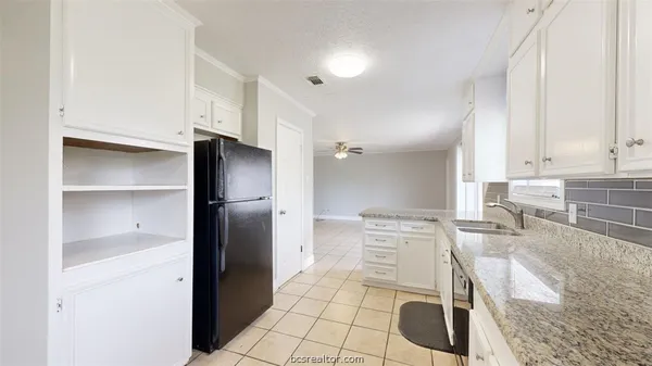 a kitchen with granite countertop a refrigerator and a sink