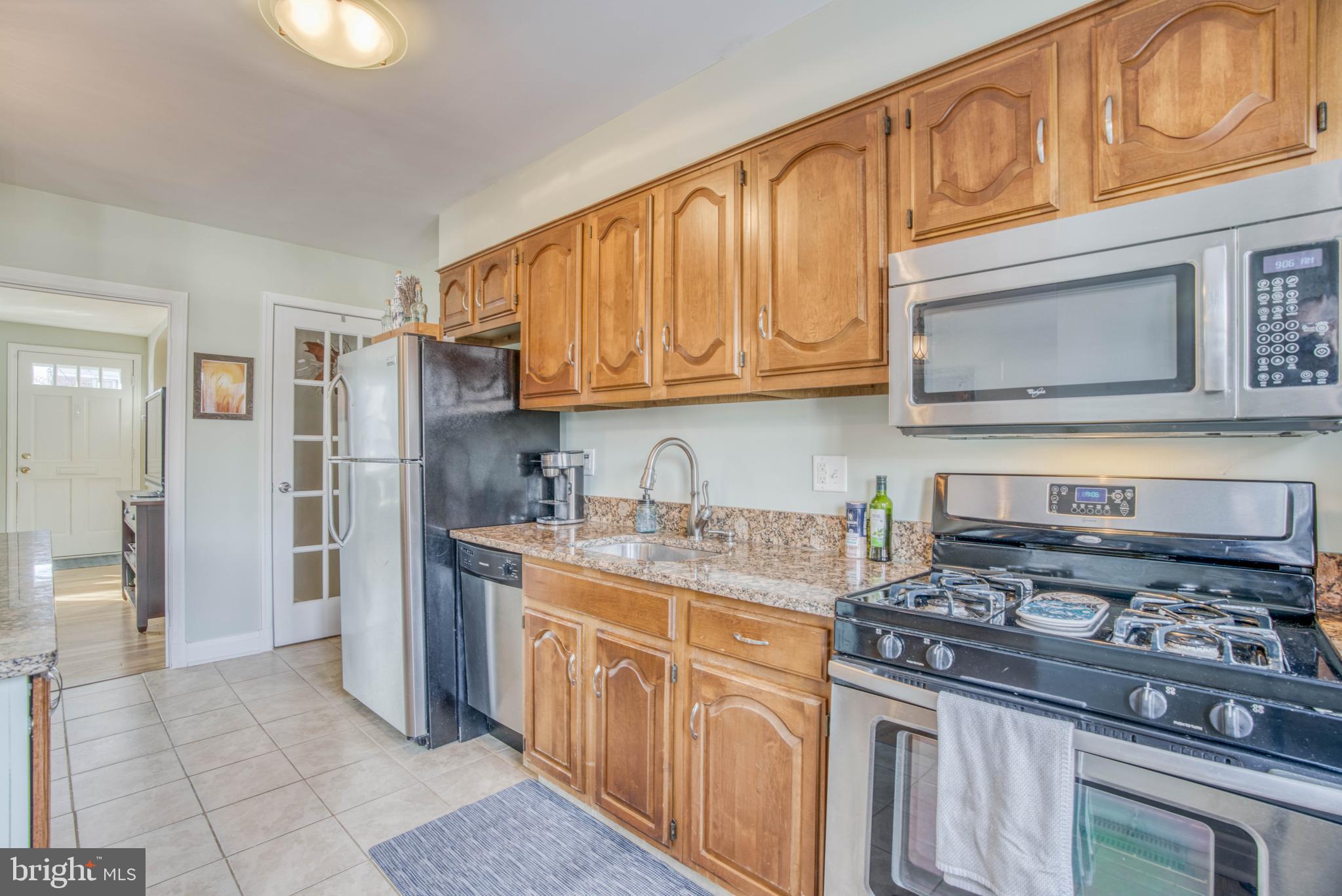 130 Hopkins Road Baltimore, MD 21212 - Photo 18 of 52 a kitchen with stainless steel appliances granite countertop a stove top oven a refrigerator a sink and dishwasher with wooden cabinets