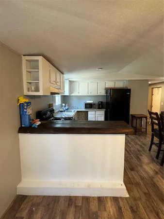a kitchen with stainless steel appliances a refrigerator a stove a sink a dining table and chairs with wooden floor
