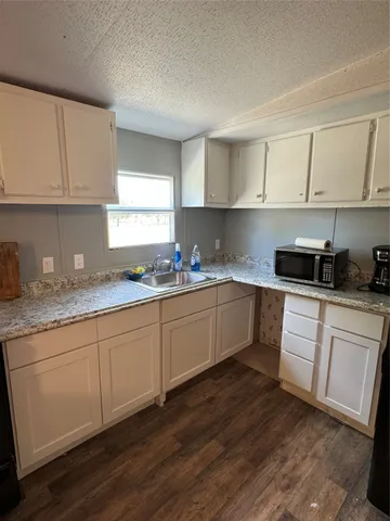 a kitchen with granite countertop white cabinets sink and appliances