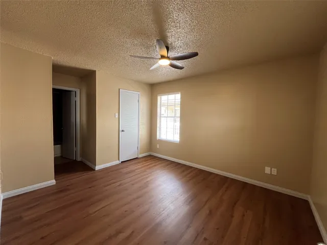 an empty room with wooden floor chandelier fan and windows
