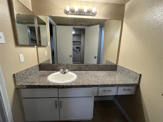 a bathroom with a granite countertop sink and a mirror