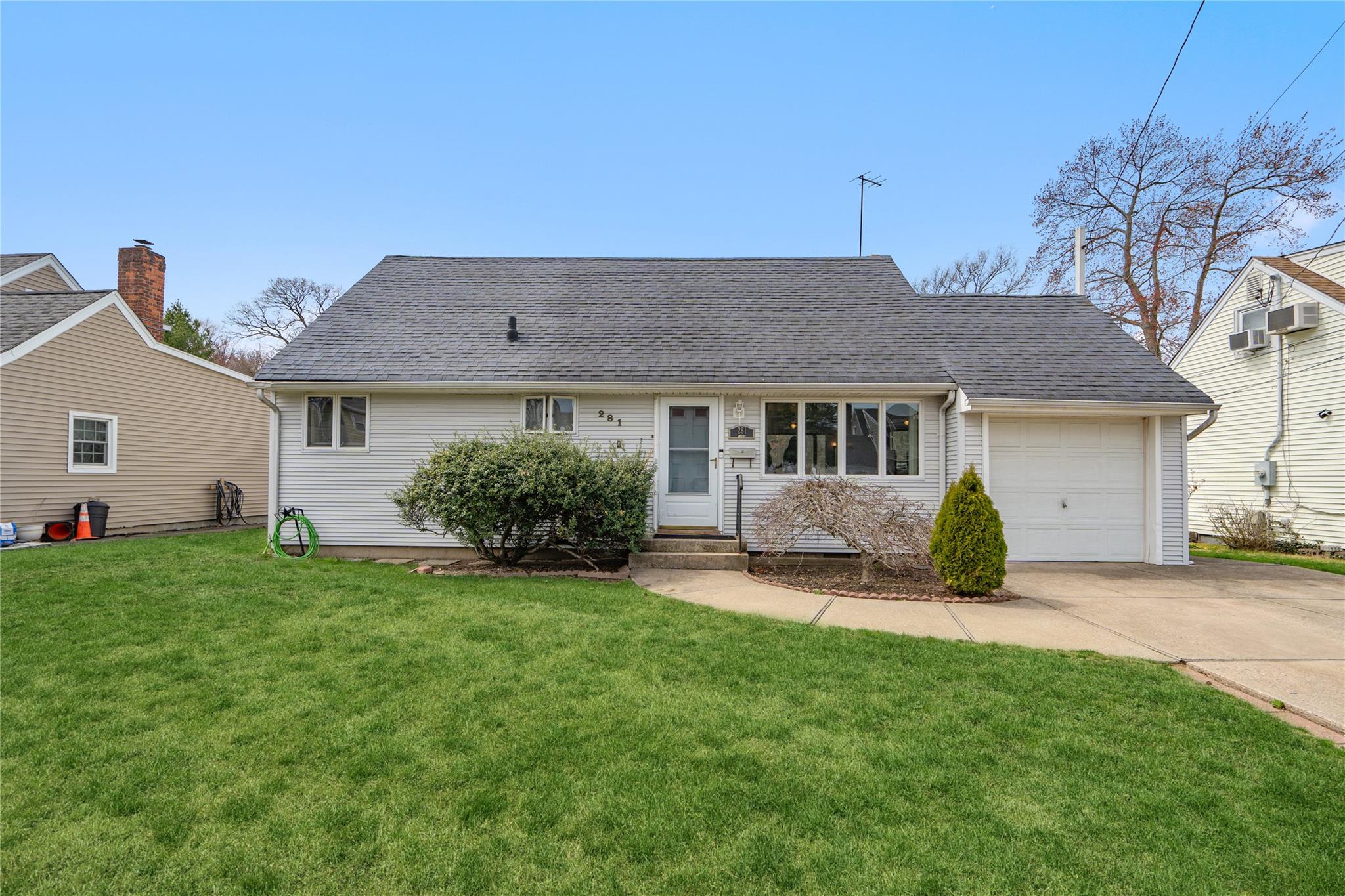 View of front of property featuring a garage, a shingled roof, driveway, and a front lawn