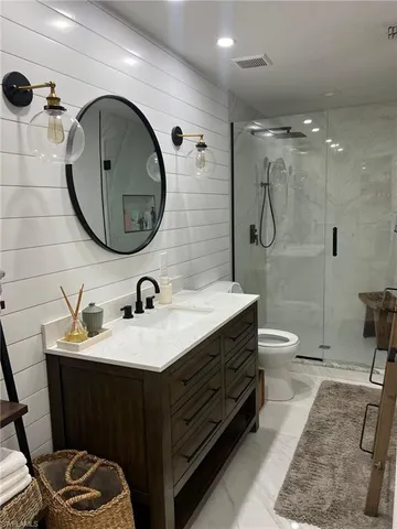a bathroom with a double vanity sink toilet mirror and shower