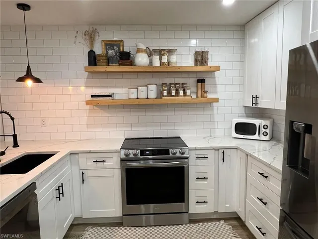 a kitchen with stainless steel appliances granite countertop a sink a stove and cabinets