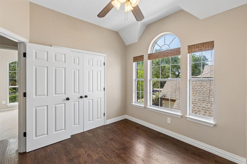 2925 Sunset Ridge McKinney, TX 75072 - Photo 17 of 33 Charming upstairs bedroom featuring rich hardwood flooring, vaulted ceilings, elegant architectural windows, and abundant natural light that creates a warm and welcoming atmosphere.