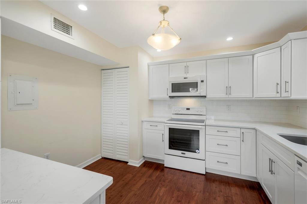 4160 Crayton Road, Unit A8 Naples, FL 34103 - Photo 17 of 26 a kitchen with granite countertop white cabinets stainless steel appliances and wooden floor