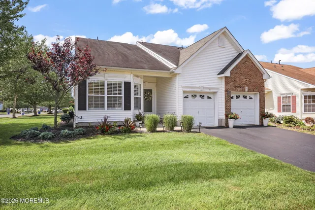a front view of a house with a garden and trees