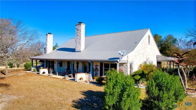 a view of a white house with large windows and table and chairs under an umbrella