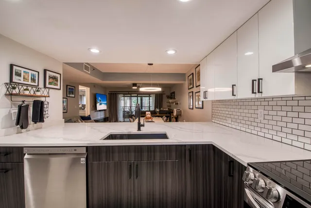 a kitchen with kitchen island a counter top space a large window and stainless steel appliances