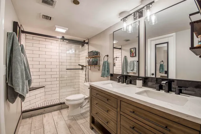 a bathroom with double sink shower and a mirror