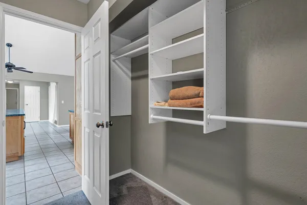 an empty room with closet and a chandelier fan