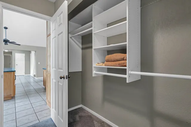 an empty room with closet and a chandelier fan